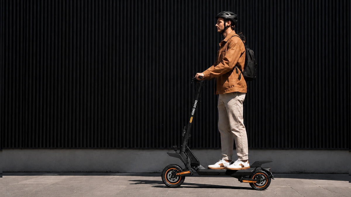 Rider on a Kingsong N12T3 electric scooter beside a city building